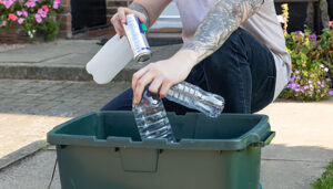A residents puts plastic bottles in their recycling box.