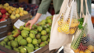 A shopper putting fruit in a reusable net bag.