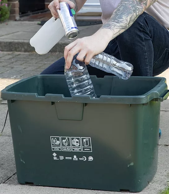 Image of a resident sorting plastic bottles into a recycling box.